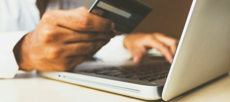 Person holding a credit card while using a laptop.