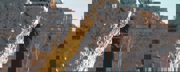 Ancient stone ruins with a historic mosque featuring a large dome in the background.