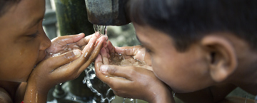 Two young boys drinking water, an act that invalidates fasting according to Islamic teachings.