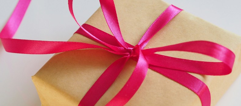 Gift wrapped in brown paper with a bright pink ribbon tied in a bow.