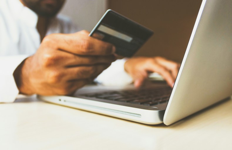 Man holding your bank card and computer in front of him